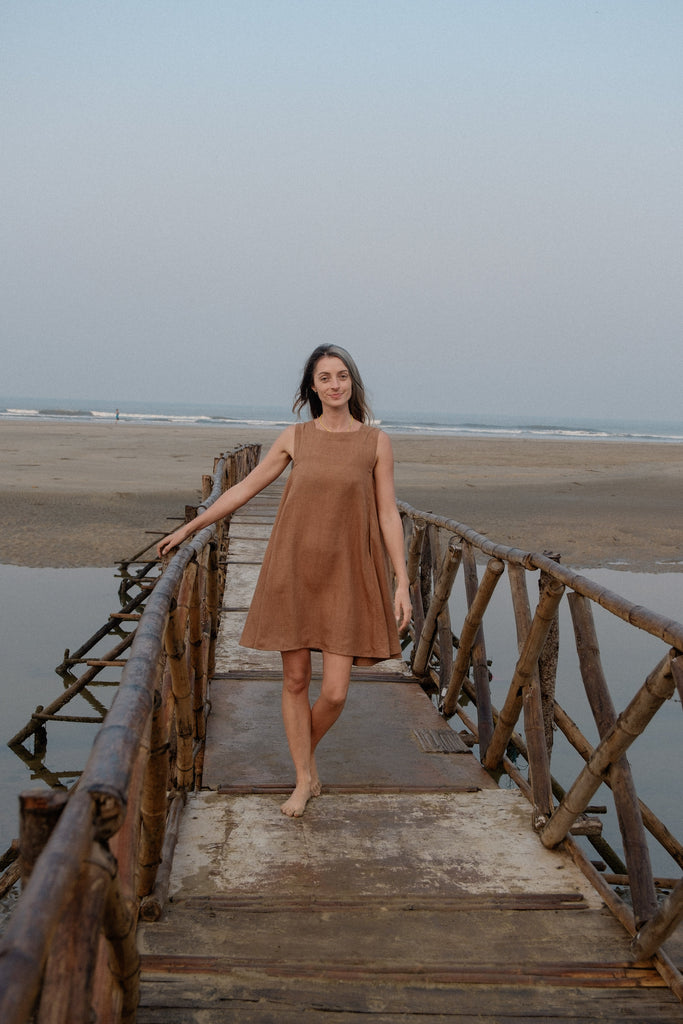 This noon dress is made in collaboration between Erica Kim and World of Crow, it has linen fabric, Brown rustic color, sleeveless, above knee-length dress, it is sustainably made and true to size