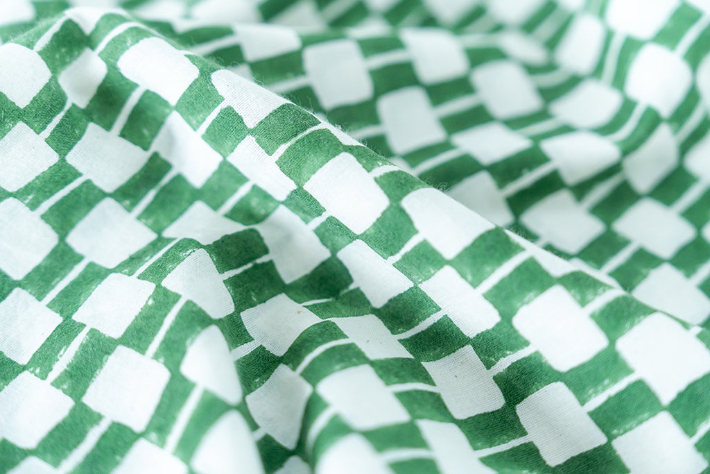 Green and white hand block-printed dress made from 100% organic cotton, featuring a front button opening and high-low hemline. Crafted over 5 days using azo-free dyes, the lightweight, non-stretchy fabric feels soft and breathable on the skin. Each piece is ethically made and uniquely one-of-a-kind, with subtle variations in print and color that highlight its artisanal nature. Falls 42” from the shoulder, offering a relaxed silhouette that fits true to size.