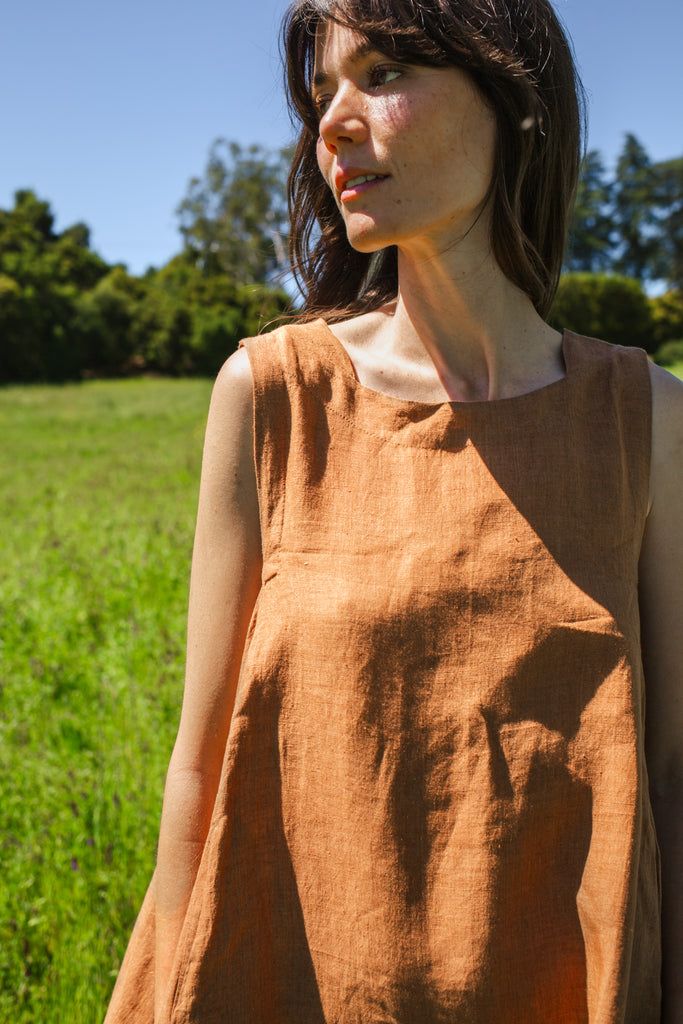 This noon dress is made in collaboration between Erica Kim and World of Crow, it has linen fabric, Brown rustic color, sleeveless, above knee-length dress, it is sustainably made and true to size