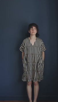 Women's black striped cotton midi dress with a V-neck, short sleeves, side pockets, and a relaxed fit. Breathable handcrafted summer dress for casual, work, and vacation wear.