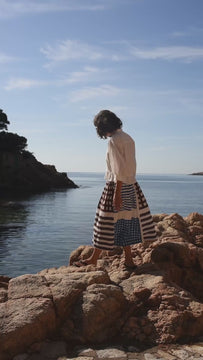 Women's midi skirt in off-white featuring a bold multi-panel geometric print with blue and brown stripes and check patterns. Crafted from breathable handwoven cotton, it has a relaxed A-line silhouette, soft gathered elastic waistband, and fluid drape for effortless everyday comfort and artisanal style.